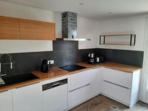 a kitchen with white cabinets and wooden counter tops at Gîte spacieux avec grand jardin, à proximité de Vichy et attractions, tout confort inclus - FR-1-489-486 in Rongères