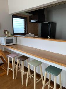 a kitchen with a counter with three stools at Ao to Yuuhi - Vacation STAY 34462v in Tateyama