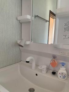 La salle de bains est pourvue d'un lavabo, d'un miroir et d'un robinet. dans l'établissement Ao to Yuuhi - Vacation STAY 34462v, à Tateyama