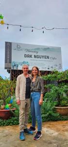 a man and a woman standing in front of a sign at Dak Nguyen Homestay DakLak in Dak Lak