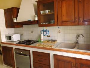 una cucina con armadi in legno, lavandino e forno a microonde di Appartamento La Dimora Siciliana a Trapani