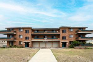 a large brick building with a driveway in front of it at Seabreeze 3 in Tuncurry