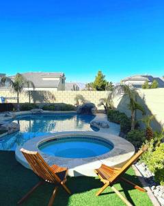 a patio with two chairs and a swimming pool at CasAHermosa Cozy getaway ! in Las Vegas