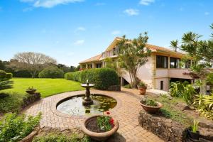 a garden with a fountain in front of a house at Riana in Coorabell Creek