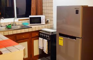 a kitchen with a stainless steel refrigerator and a microwave at Studio Iti Fare Tepua Lodge in Uturoa