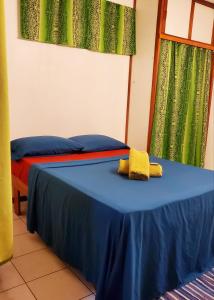 Zimmer mit 2 Betten, blauer Bettwäsche und grünen Vorhängen in der Unterkunft Studio Iti Fare Tepua Lodge in Uturoa
