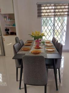 a dining room table with chairs and a table with food at Freesia Haus in Kota Bharu