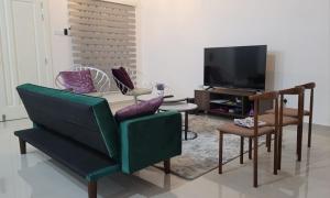 a living room with a green couch and a table at Freesia Haus in Kota Bharu