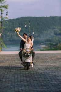 una sposa e uno sposo che cavalcano su uno scooter di Labe Hotel Phú Quốc - Sunset Town - Địa Trung Hải a Phu Quoc