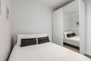 a white bedroom with a bed and a mirror at 'Swanston Central' Wellness-infused City Living in Melbourne