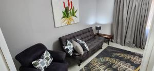 - un salon avec un canapé et une chaise dans l'établissement Cottage Rose, à Bloemfontein