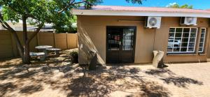 a small house with a door and a tree at Cottage Rose in Bloemfontein