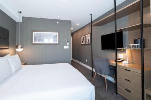 a bedroom with a bed and a desk and a television at Sandman Signature Calgary Airport Hotel in Calgary