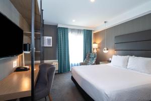 um quarto de hotel com uma cama, uma secretária e uma televisão em Sandman Signature Calgary Airport Hotel em Calgary