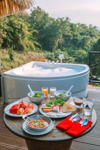 a table with plates of food and a bath tub at แคมป์ต๊ะต่อนยอน แม่กำปอง เชียงใหม่ CAMP Ta-Torn-Yorn Maekampong Chiang Mai in Mae On
