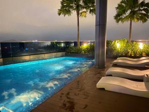 a pool on the roof of a building with palm trees at Eaton Residences at Leo in Kuala Lumpur