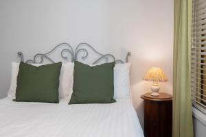 ein Bett mit grünen Kissen und einer Lampe auf dem Tisch in der Unterkunft 'The Elizabeth' A Romantic Garden Retreat for Two in Newcastle