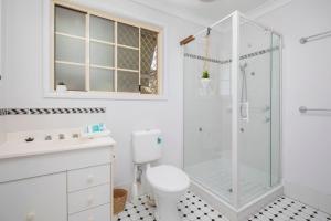 a white bathroom with a shower and a toilet at 'The Elizabeth' A Romantic Garden Retreat for Two in Newcastle +6 photos