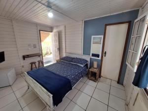 a bedroom with a bed with a blue comforter at Canto Boreal - Suítes e Estúdios in Camburi