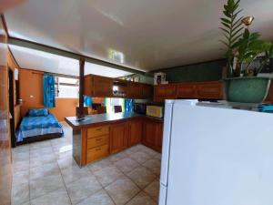 a kitchen with wooden cabinets and a white refrigerator at Studio Poe 1 Room Fare Tepua Lodge in Uturoa