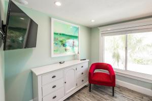 een rode stoel en een wit dressoir in een kamer bij Blissful Bay at Bayside Bungalow in Anna Maria