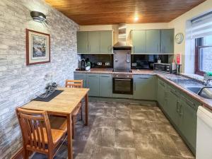 una cucina con armadi verdi e tavolo in legno di Apple Tree Cottage a Threlkeld