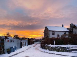 a house in the snow with a sunset in the background at Apple Tree Cottage in Threlkeld