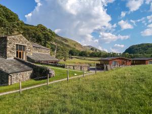 a farm with a stone building and a grass field at Bram Crag Barn in Legburthwaite