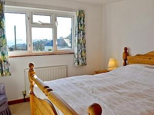 a bedroom with a large bed and two windows at Ponsgwedhen in Coverack