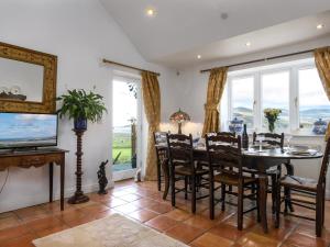 a dining room with a table and chairs and windows at Treetops in Fairbourne