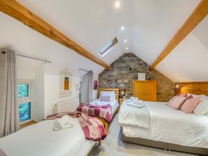 a attic bedroom with two beds and a stone wall at Noddfa in Harlech