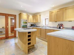 a large kitchen with wooden cabinets and a counter top at Gorst Farm Barn in Great Eccleston