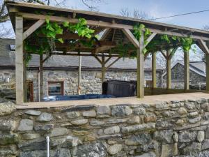 a stone wall with a pergola over a patio at Kris Kin in Brynkir