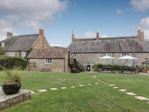 a large stone building with a grass yard in front of it at Park Farmhouse in Chideock