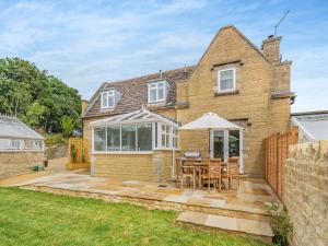 a house with a patio with a table and chairs at The Mill Lodge in Malmesbury