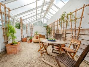 a greenhouse with a table and chairs and potted plants at The Mill Lodge in Malmesbury