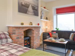 uma sala de estar com uma lareira de tijolos e um sofá em Hideaway Studio Apartment em Denby Dale