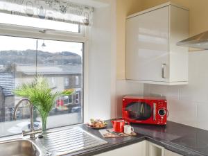 uma cozinha com um micro-ondas vermelho e uma janela em Hideaway Studio Apartment em Denby Dale