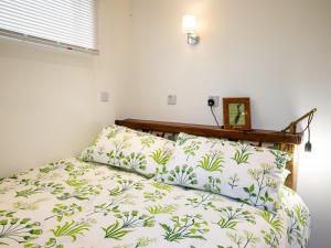 een slaapkamer met een bed met groene en witte lakens bij Sunrise Cabin in East Ilsley