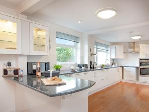 a kitchen with white cabinets and a black counter top at Bay Tree in Porthscatho