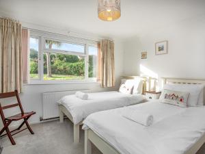 a bedroom with two beds and a chair and a window at Bay Tree in Porthscatho