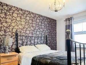 a bedroom with a bed and a wall with floral wallpaper at Royal House in Ilkeston