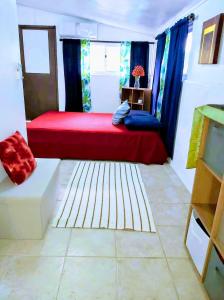 Cette chambre comprend un lit rouge et des rideaux bleus. dans l'établissement Studio Nui 1 Room Fare Tepua Lodge, à Uturoa