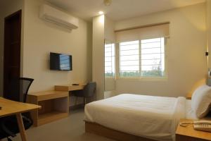 a bedroom with a bed and a desk and a television at Dreamotel Luxury Suites in Kanjikode
