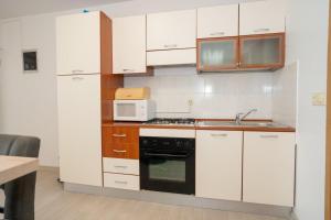 a kitchen with white cabinets and a sink and a microwave at Apartment Danka - parking and grill in Novalja