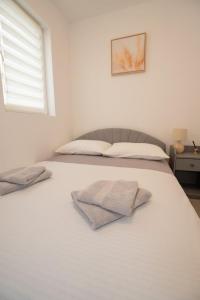 a bedroom with a white bed with two towels on it at Apartment Danka - parking and grill in Novalja