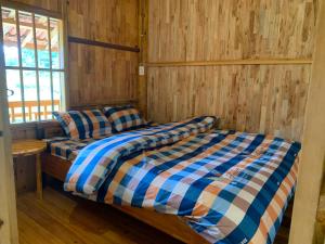 two beds in a room with wooden walls and a window at Hoàng nam Homestay in Quang Ba