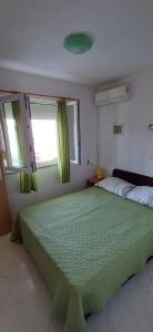 ein Schlafzimmer mit einem großen grünen Bett und zwei Fenstern in der Unterkunft Apartment More 1 - sea front in Savar