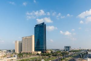 ein hohes Gebäude mitten in einer Stadt in der Unterkunft Dusit Thani Abu Dhabi in Abu Dhabi