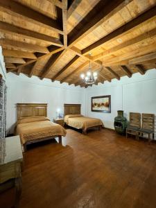 two beds in a large room with wooden ceilings at Los Azufres Spa Natural in Los Azufres